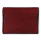 A closed red bi-fold credit card holder with visible stitching and a embossed logo on the front of the leather story